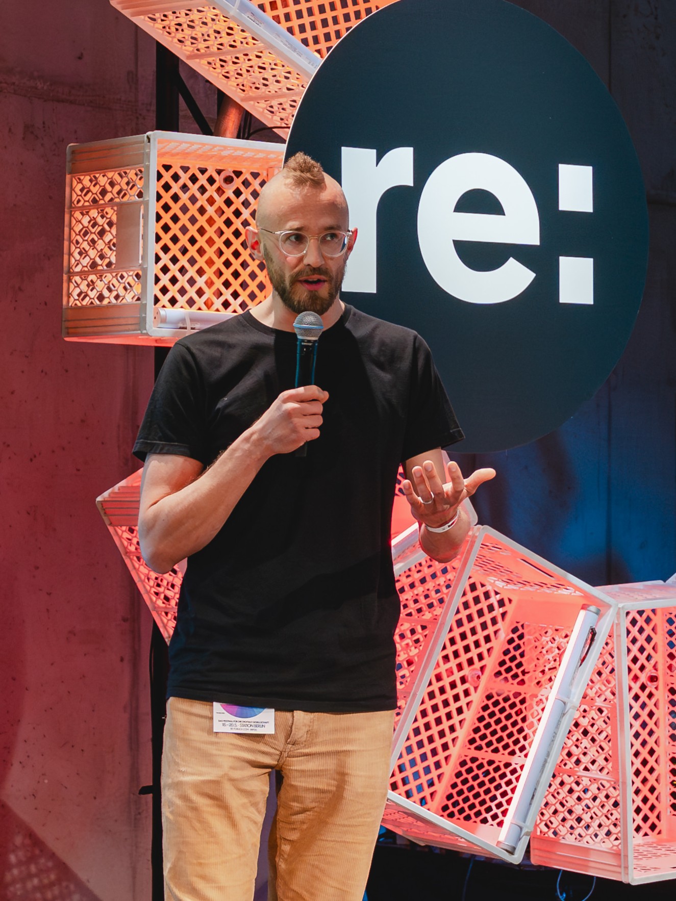 Lukas Marzi spricht mit Mikrofon auf einer Bühne