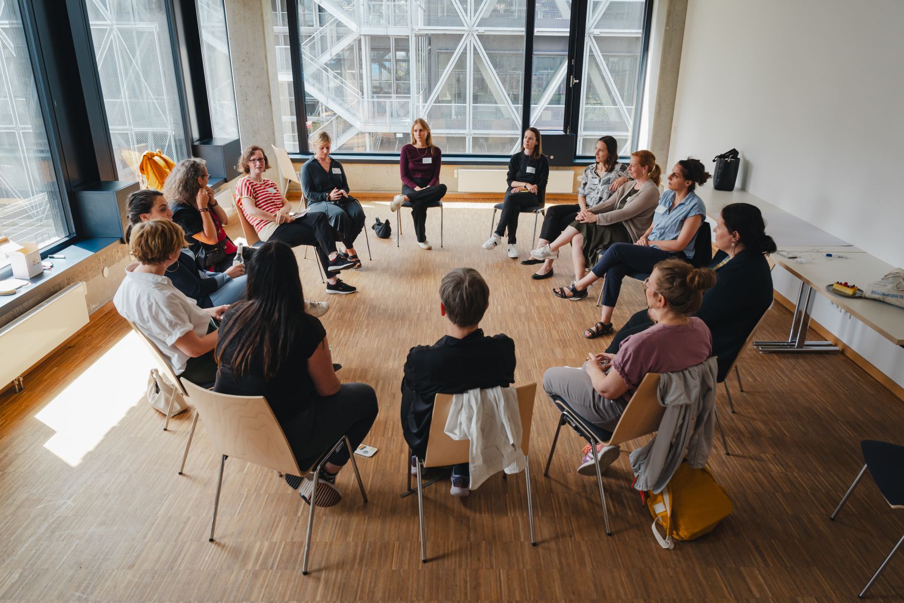 Rund vierzehn Teilnehmende im Stuhlkreis bei einem Workshop